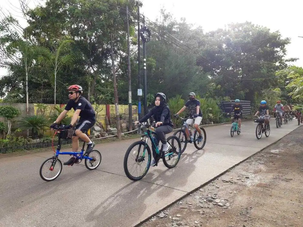 cowok dan cewek ramai bersepeda melewati jalan danau tanjung bunga