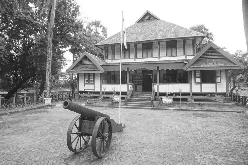 rumah adat di benteng somba opu makassar dengan meriam di depannyabe
